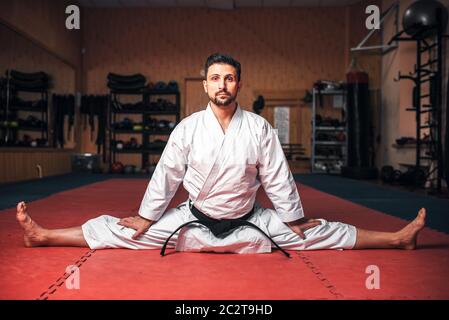 Arts martiaux karate master en kimono blanc et black belt doing stretching de l'exercice dans la salle de sport Banque D'Images