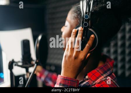 Jeune femme dans les écouteurs chansons en studio d'enregistrement audio. Musicien à l'écoute de la composition, le mélange de musique professionnels