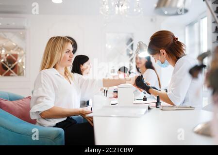 Groupe de copines se détendre sur la procédure de manucure dans le salon de beauté. Esthéticienne professionnelle et clients féminins, soins des ongles au spa, soins des ongles Banque D'Images