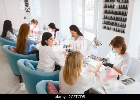 Groupe de copines se détendre sur la procédure de manucure dans le salon de beauté. Esthéticienne professionnelle et clients féminins, soins des ongles en studio spa, Fingernail tr Banque D'Images