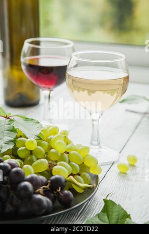 Deux verres avec différentes variétés de vin et une assiette avec différents raisins mûrs. Rouge ou blanc ? Votre choix ! Banque D'Images