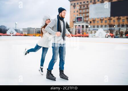 L'amour heureux couple pose sur patinoire. Hiver patinage sur open air, loisirs actifs, homme et femme, à l'ensemble des patins Banque D'Images