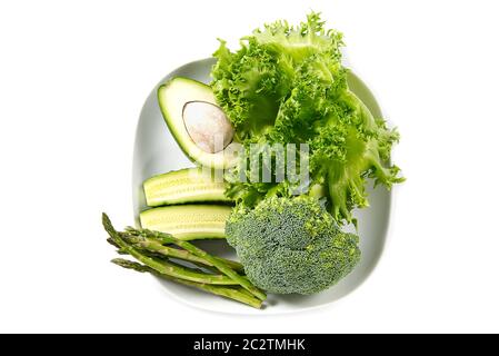 Bouquet de légumes isolés sur fond blanc. Pile de légumes frais sur une assiette blanche. Régime de légumes verts. Banque D'Images