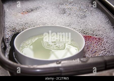 Bols et tasses en porcelaine et assiettes dans un bol de lavage avec bulles de savon, en attente d'être nettoyés Banque D'Images