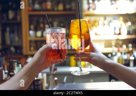 Femme et homme levant des verres de queues de cochon au bar Banque D'Images