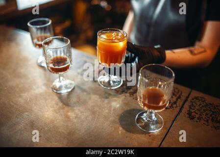Barman Femme tenant un verre à cocktail sur le comptoir du bar. Boire de l'alcool de préparation. Barman dans un pub de travail Banque D'Images