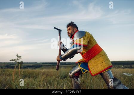 Le chevalier médiéval ancien en armure tient hache, grand tournoi. Ancien guerrier blindé en armure posant dans le champ Banque D'Images