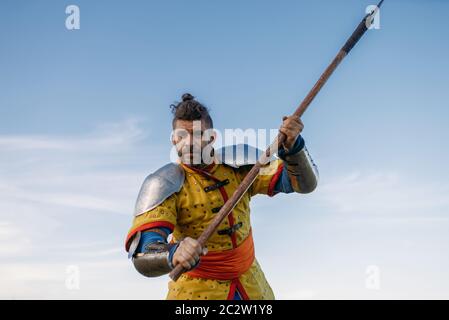 Le chevalier médiéval ancien en armure tient hache, grand tournoi. Ancien guerrier blindé en armure posant dans le champ Banque D'Images