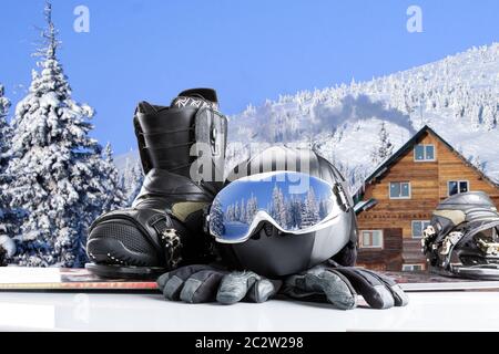 Lunettes de sport d'hiver, snowboard boot, casque et gants sur fond de montagnes d'hiver Banque D'Images