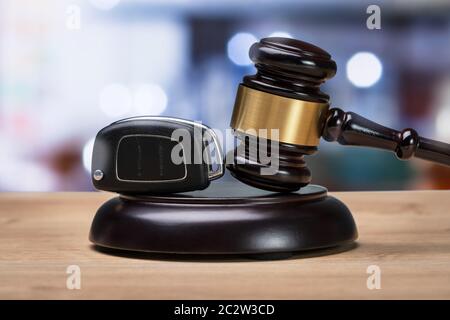 Close-up d'un marteau et clé de voiture sur le bloc de frappe plus de bureau en bois Banque D'Images