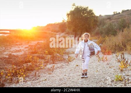 Astronaute futuriste fille enfant avec uniforme blanc pleine longueur et casque portant des chaussures argentées à l'extérieur Banque D'Images