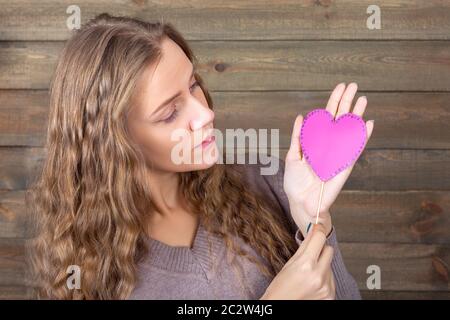 Jeune femme avec coeur rose à la main, fond de bois. Photos amusantes et accessoires accessoires pour tire Banque D'Images