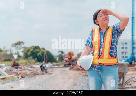 Engineering woman holding a white casque de sécurité debout devant le site de construction. Concepts pour le contrôle et la vérification de la construction acc Banque D'Images