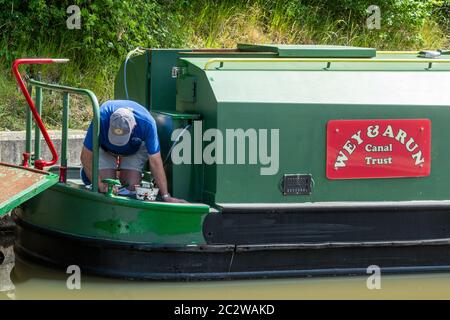 Wey et Arun Canal Trust travaillent bénévolement, homme peint un bateau à rames, West Sussex, Royaume-Uni Banque D'Images