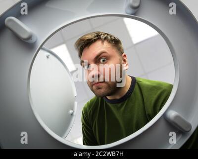 Homme dans la salle de bains regardant dans le bol des toilettes Banque D'Images