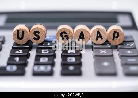 Close-up de table ronde en bois avec des blocs de texte US GAAP sur les boutons de la calculatrice Banque D'Images