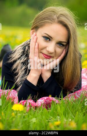 Jolie jeune fille se détendant dans l'herbe verte. Banque D'Images