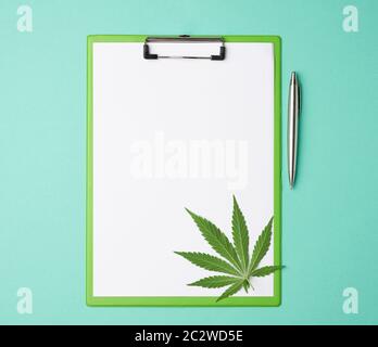 feuille verte de marijuana et un support pour papiers avec feuilles blanches vides sur fond vert, vue du dessus, place pour une inscription Banque D'Images