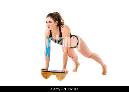 Kinesio tape fille, exercices push-up. Attrayante jeune femme sportive faisant exercice poussé vers le haut en pleine longueur isolée sur le dos blanc Banque D'Images