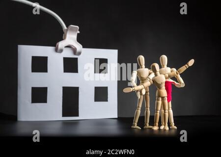 Famille de figures en bois près de maison en papier Banque D'Images