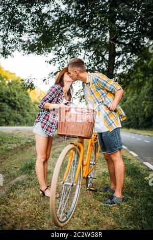 Jeune homme et femme embrassant à la date romantique. Couple heureux amour avec vélo vintage. Petit ami et petite amie ensemble, vélo rétro Banque D'Images