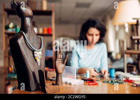 Collier artisan sur un mannequin en bois, travaux d'aiguille. Artisan des femmes sur le lieu de travail sur l'arrière-plan Banque D'Images