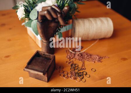 Accessoires pour les travaux d'aiguille, peu d'anneaux en métal et en bois décoratif sur la table, la main libre. Des bijoux, bijouterie faisant Banque D'Images