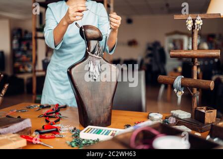 Personne de sexe féminin essayant sur collier artisan sur un mannequin en bois, travaux d'aiguille. Artisan des femmes sur le lieu de travail en art studio Banque D'Images