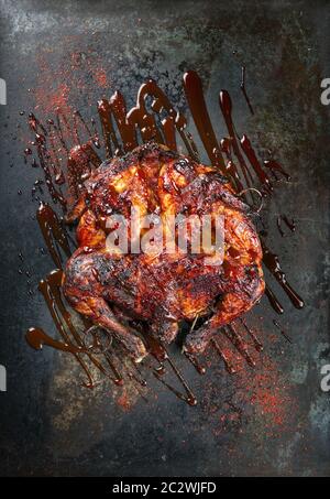 Poulet barbecue spatchcoché au barbecue al mattone avec sauce Chili chaude comme vue de dessus sur une vieille tôle Banque D'Images