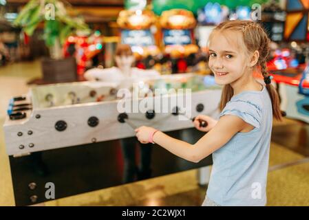 Happy girl au soccer sur table d'enfants game center. Female enfant s'amuser sur l'aire de l'intérieur. Kid joue sur la machine en football amusem Banque D'Images