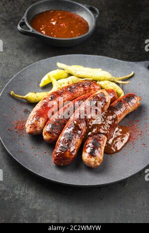 Barbecue traditionnel allemand Bratwurst avec sauce chaude et peperoni comme un gros plan sur une plaque en fonte de conception moderne