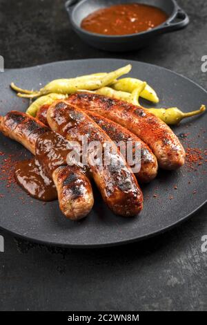 Barbecue traditionnel allemand Bratwurst avec sauce chaude et peperoni comme un gros plan sur une plaque en fonte de conception moderne