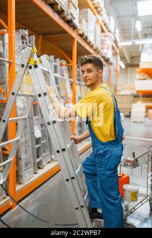 Un constructeur de sexe masculin monte les escaliers dans un magasin de matériel. Constructeur en uniforme regarder les marchandises dans le magasin de bricolage Banque D'Images
