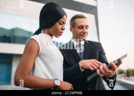 Business Woman et homme regarde sur un écran d'ordinateur portable, l'extérieur réunion de partenaires, immeuble de bureaux modernes sur l'arrière-plan, les négociations du partenariat Banque D'Images