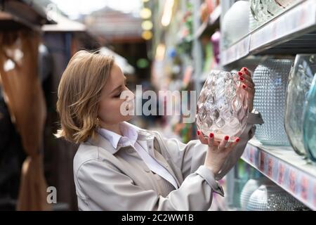 Mignonne femme acheteur choix dans le jardin magasin vase en cristal pour fleurs. Banque D'Images