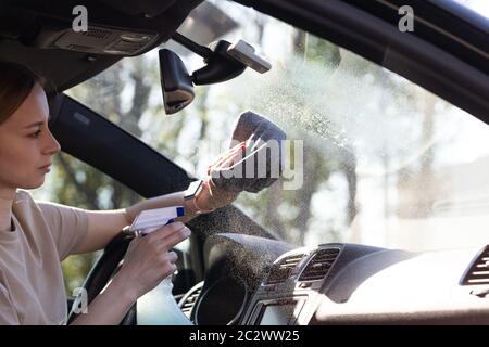 Gros plan de femme conducteur nettoyant pare-brise de voiture avec spray, lingettes avec microfibre de la poussière et de la saleté. Banque D'Images