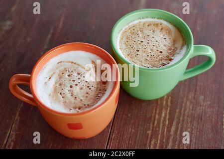 Deux tasses de cappuccino parfumé sur un papier de couverture en bois. Mousse de lait aérée d'une boisson chaude. Boisson au café avec lait Banque D'Images