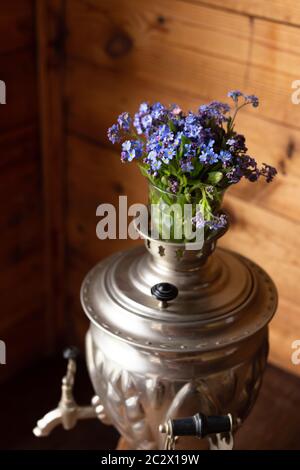 Vieux samovar en métal et un bouquet de fleurs bleues sur fond de bois Banque D'Images