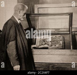 Retourner une page du Livre de Kells, qui aurait été créé c. 800 AD, dans la vieille bibliothèque et la salle longue à Trinity College au début des années 1920, Dublin City, Irlande. Initialement photographié par Clifton Adams (1890-1934) pour 'Ireland: The Rock Wharce I was hewn', un reportage du magazine National Geographic de mars 1927. Banque D'Images