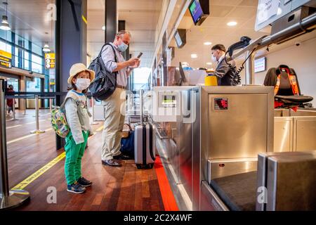 Un homme et son fils sont vus porter des masques faciaux au point d'enregistrement à l'aéroport. Le premier groupe de voyageurs part de l'aéroport de Rotterdam la Haye avec Transavia au Portugal en vacances. Tous les voyageurs sont tenus de porter des masques dans les restaurants et les salles de départ, conformément aux directives de mesure du coronavirus des fêtes des pays européens. Banque D'Images