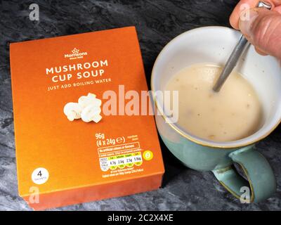 Soupe aux champignons de marque Morrisons : une boîte de produit et un sachet de soupe sèche mélangé à de l'eau bouillante, remués dans une tasse. Banque D'Images