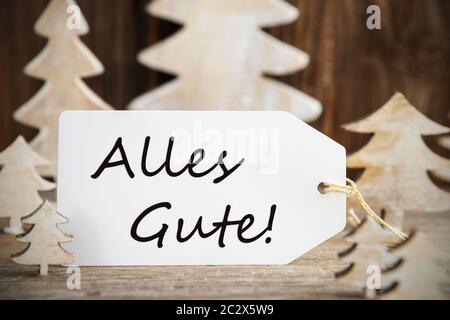 Étiquette avec texte allemand Alles Gute signifie meilleurs voeux. Arbre de Noël en bois blanc comme décoration. Fond en bois brun Banque D'Images