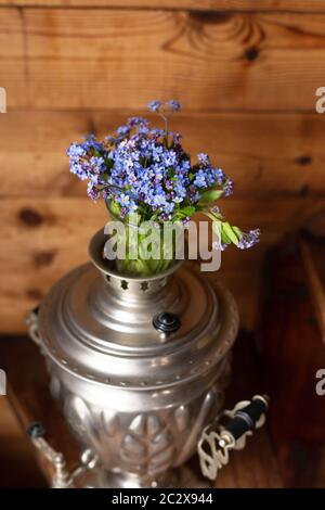 Vieux samovar en métal et un bouquet de fleurs bleues sur fond de bois Banque D'Images