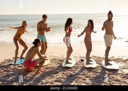 Groupe multiethnique de hommes et de femmes, surf sur la plage Banque D'Images