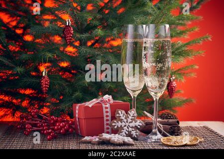 Deux verres avec champange, sapin, cadeaux, Noël et le gingembre cookies sur un fond rouge. Noël et Nouvel an. Banque D'Images