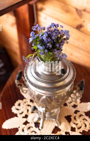 Vieux samovar en métal et un bouquet de fleurs bleues sur fond de bois Banque D'Images