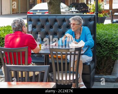 Oak Park, Illinois, États-Unis. 17 juin 2020. Deux femmes déjeunent dans un café-terrasse. Les restaurants de la région de Chicago sont désormais ouverts pour des places assises à l'extérieur avec une distance sociale appropriée. Les serveurs doivent porter des masques. Le taux d'infection par le virus COVID-19 de l'Illinois diminue plus rapidement que dans les autres États en raison de l'état de vie vigoureux à la maison et des directives de distanciation sociale. Banque D'Images