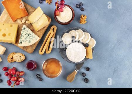 Plateau de fromages, une dose de suspension plate. Fromage bleu, Leicester rouge, Emmental, fromage de chèvre, brie et autres avec vin, fruits, Banque D'Images