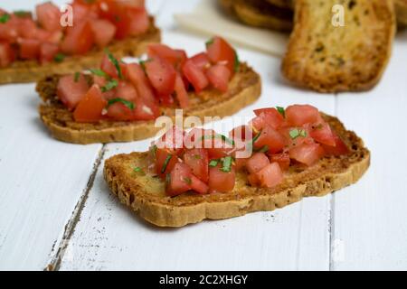 Bruschetta sur fond blanc. Bruschetta est un hors-d'œuvre italien populaire (antipasti), fait d'une crostini (pain grillé) avec des tomates en dés. Banque D'Images