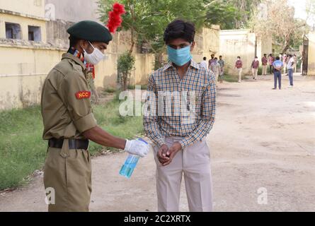 Beawar, Rajasthan, Inde, 18 juin 2020 : le cadet de la NCC (National Cadet corps) fournit un assainisseur pour les mains aux élèves lorsqu'ils arrivent à apparaître au 12e examen standard du conseil d'administration à l'école de Patel du gouvernement, pendant la cinquième phase de l'isolement de confinement de la COVID-19 à Beawar. Toutes les normes de distance sociale ont été suivies pendant l'examen. Crédit : Sumit Saraswat/Alay Live News Banque D'Images